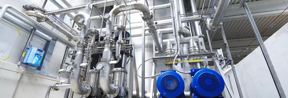 Industrial water pre-treatment system with stainless steel pipes, pumps, and gauges.